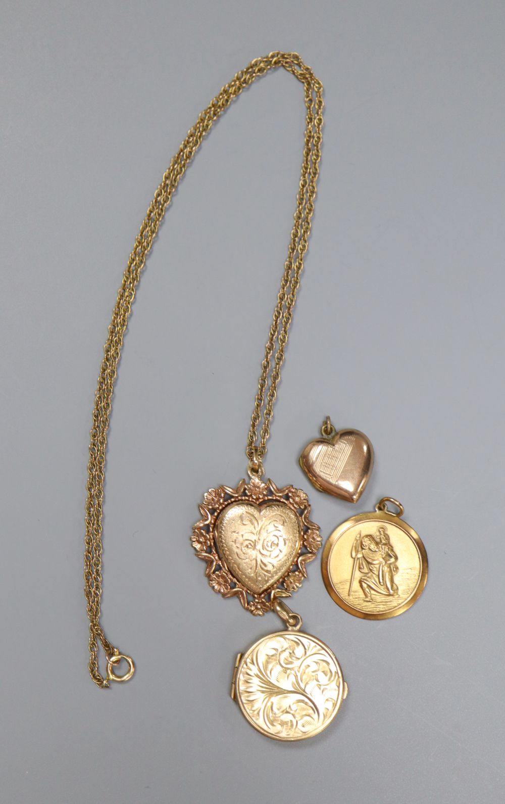 A 9ct gold heart-shaped fancy locket on chain, an engraved circular locket, a small heart-shaped locket and a St Christopher medallion